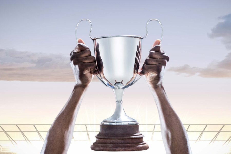 Hands holding champions trophy against stadium in background